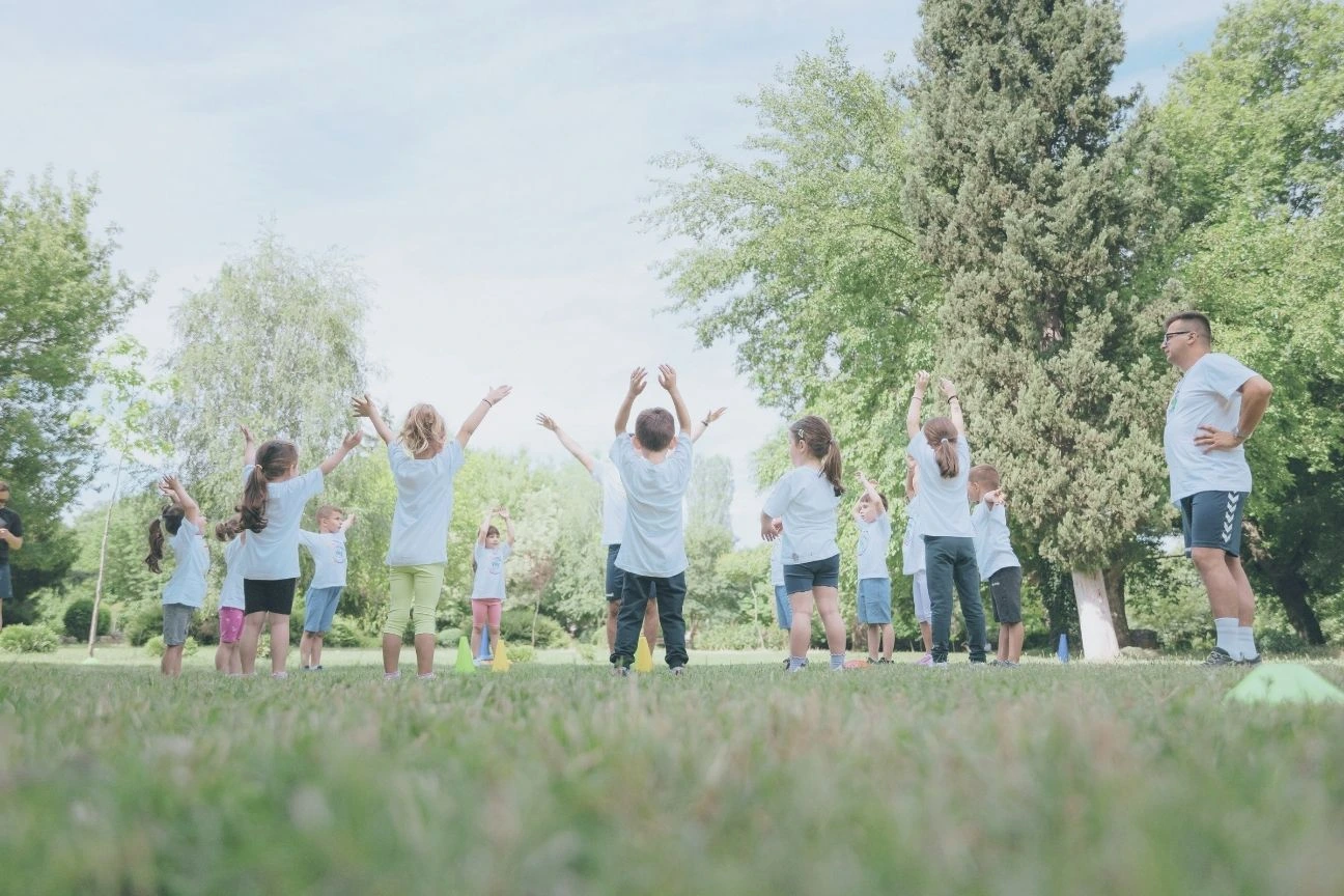 Photo montrant une groupe de pratiquants de 8-12 ans en train de s'échauffer avec un éducateur sportif
